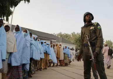 Un soldado junto a un grupo de niñas previamente secuestradas en su internado en el norte de Nigeria (Foto de - / AFP)