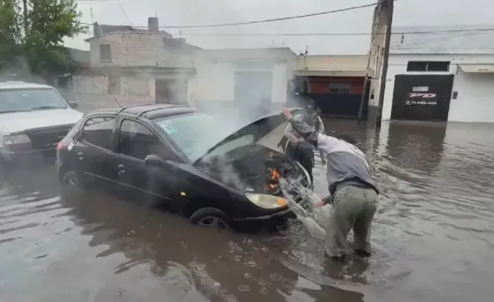 Un auto se prendió fuego en una calle inundada y apagaron el incendio con el agua de la lluvia.